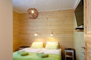 a bedroom with a wooden wall with a bed and a chandelier at Villa Kilpikonna in Mikkeli