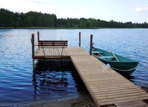 a wooden dock with a bench and a boat on the water at Villa Kilpikonna in Mikkeli