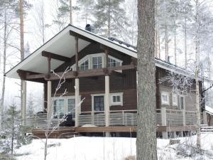 una cabaña de madera en el bosque en la nieve en Villa Kilpikonna, en Mikkeli