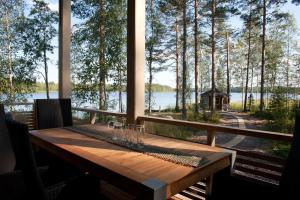 a wooden table on a porch with a view of a lake at Villa Kilpikonna in Mikkeli