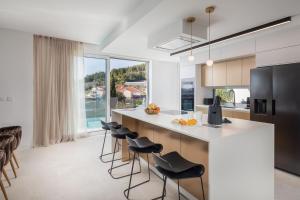 una cocina con una isla con taburetes y encimera en Villa Golden Hill with dream View prof Gym Wellness near Split en Podstrana