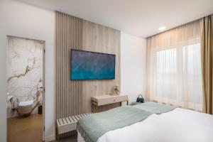 1 dormitorio con 1 cama y TV en la pared en Villa Golden Hill with dream View prof Gym Wellness near Split en Podstrana