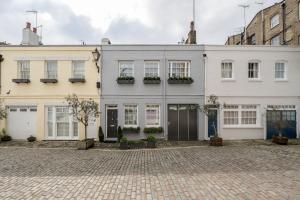 Luxurious Mews House Next to Hyde Park في لندن: بيت ابيض بنوافذ وابواب على شارع طوب