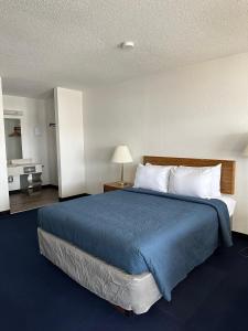 1 dormitorio con 1 cama grande con manta azul en Bayside Inn, en Saint Ignace