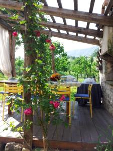 una mesa y sillas en una terraza de madera con rosas en Casa Shalom en Pennabilli