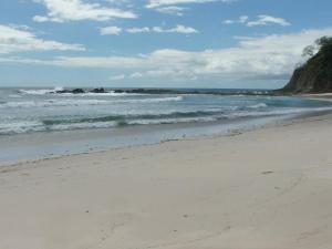 una playa de arena con olas en el océano en Sámara Tarantela Houses, Casa Coyol, en Sámara
