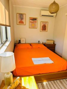 1 dormitorio con 1 cama con colcha de color naranja en Grandpa’s cottage, en Nea Makri