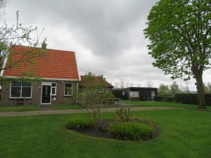een huis met een oranje dak op een groene tuin bij Vakantiewoning De Klaproos in Boyl