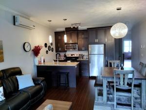 eine Küche und ein Wohnzimmer mit einem Sofa und einem Tisch in der Unterkunft Le 201 Champlain Bromont in Bromont