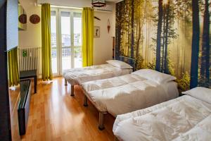 three beds in a room with yellow curtains at Attico con Vista in Turin