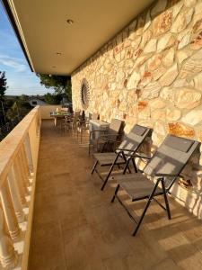 a patio with chairs and a stone wall at Heraklia villa sea view in Nea Irakleia