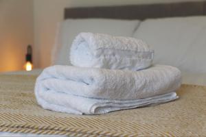 a stack of towels sitting on top of a bed at 4ft Double bed with Parking & Wi-fi in Modern Townhouse in Long Eaton in Long Eaton