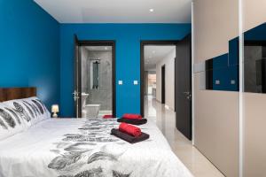a bedroom with blue walls and a bed with red pillows at Modern 3BR Stylish Apartment with large Balcony - Close to St Julians and St Georges Bay in Is-Swieqi