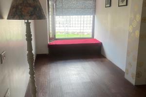 a room with a window with a red couch in front at 2BHK Apartment In Mansion Near Nainital Lake in Nainital