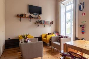 een woonkamer met stoelen en een tv aan de muur bij Despertar Saudade in Coimbra