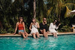 vier vrouwen naast een zwembad bij TUK Tropical Boutique Resort Jan Thiel in Willemstad