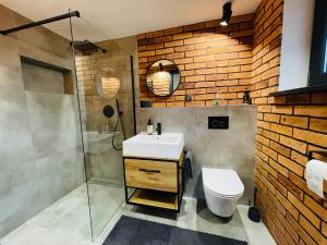 a bathroom with a sink toilet and a brick wall at Balans nad Jeziorem in Ślesin