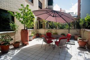 a patio with a table and chairs and an umbrella at UN JARDIN EN LA CIUDAD gran piso y super terraza en el centro By Apartamentos con aire acondicionado Logroño in Logroño