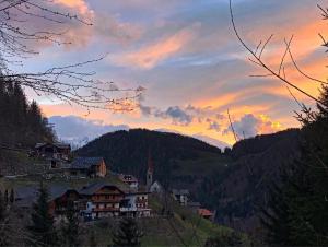 een dorp op een heuvel met een zonsondergang op de achtergrond bij Thalerhof in San Lorenzo di Sebato