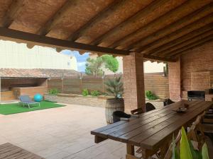une table en bois dans un patio avec un toit en bois dans l'établissement Cal General, à San Vicente de Castellet