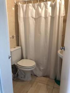 a bathroom with a toilet and a shower curtain at Cómodo apartamento en Colonia, cerca de todo in Colonia del Sacramento
