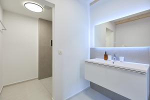 uma casa de banho branca com um lavatório e um espelho em Stone Elegance em Dubrovnik
