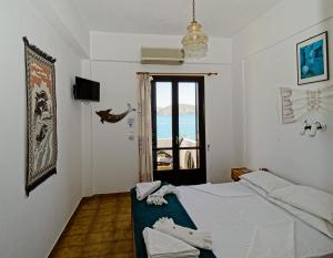 a white bedroom with a bed and a window at Dolphins in Elounda