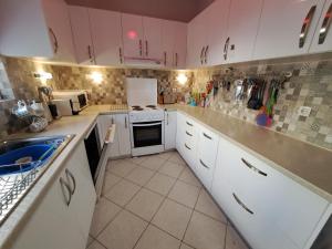 a kitchen with white cabinets and white appliances at Palm Tree Villa in Almirida