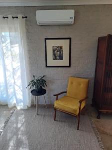 a living room with a yellow chair and a plant at The Mustard Seed Guesthouse in Bloemfontein