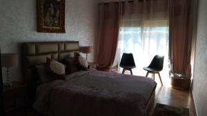 a bedroom with a bed and two chairs and a window at Villa avec piscine privée près de Casablanca Maroc in Dar Bouazza