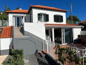 a white house with stairs and a balcony at Tropical Garden in Arco da Calheta