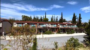 a large building with trees in the background at Village Mare Residences in Kalyves Poligirou