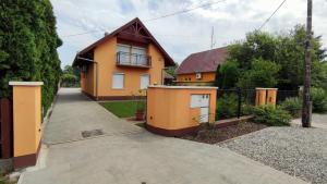 a orange house with a fence and a driveway at Vascsacsi Nyaraló in Orosháza