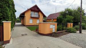 uma casa cor-de-laranja com uma cerca e uma entrada em Vascsacsi Nyaraló em Orosháza