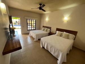 a bedroom with two beds and a ceiling fan at Natura Hotel & Villas in Zihuatanejo