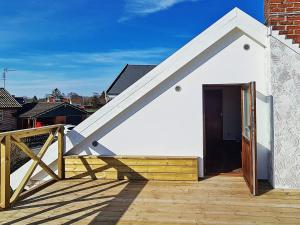 a small white building with a wooden door on a deck at 6 person holiday home in SIMRISHAMN in Simrishamn