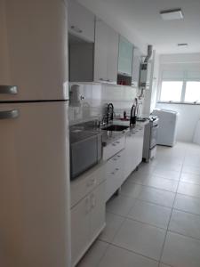 a white kitchen with a refrigerator and a sink at Apartamento confortavel Centro de Teresopolis. NOVO in Teresópolis