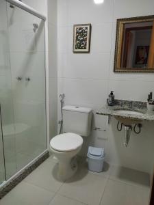 y baño blanco con aseo y ducha. en Apartamento confortavel Centro de Teresopolis. NOVO, en Teresópolis