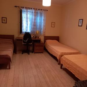 a bedroom with two beds and a desk and a window at Ksenija apartman uz more in Krasici