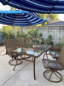 a glass table and chairs under a blue umbrella at Private Room in Los Angeles LA with TV & WIFI & AC & View of Hollywood Sign & Private Fridge & Shared Kitchen!!! in Los Angeles