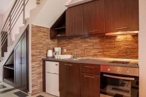 a kitchen with wooden cabinets and a brick wall at Village Mare Residences in Kalyves Poligirou