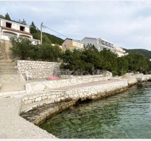 a body of water with a rock wall and a red frisbee at Villa M in Neum