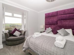 a bedroom with a large bed and a chair at The Hideaway in Kingsbridge