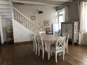 a dining room with a table and chairs and a staircase at Maison de ville confortable 200m de la mer in Le Château-dʼOléron