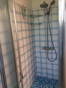 uma casa de banho com um chuveiro com azulejos azuis e brancos em La maisonnette des vacances em Saint-Georges-dʼOléron