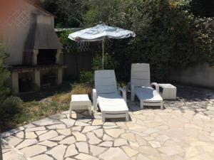 trzy krzesła i parasol na kamiennym patio w obiekcie La maisonnette des vacances w mieście Saint-Georges-dʼOléron