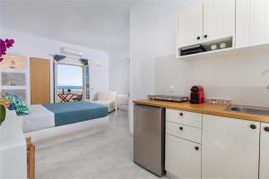 a bedroom with a bed and a kitchen with a view of the ocean at La Mer Seaside Apartments in Drios