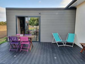 a deck with chairs and a wooden table and chairs at Charmant appartement au calme in Saint-Romain-la-Motte