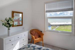 a bedroom with a window and a chair and a dresser at Seaview Beach House in Norwich