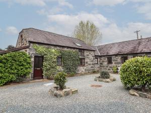 an old stone house with a courtyard in front of it at Gamekeepers Cottage in Conwy